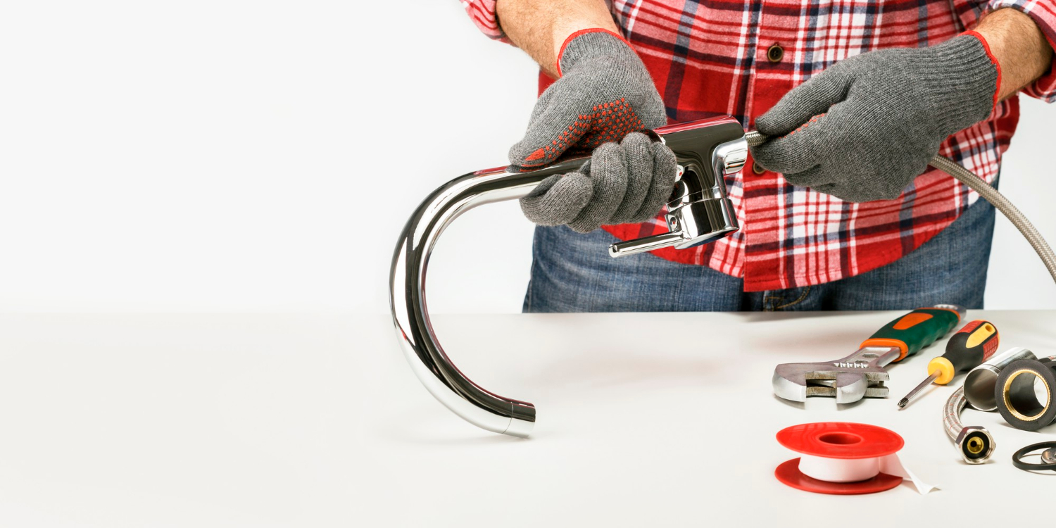 plumber-screwing-plumbing-fitting-in-faucet-against-gray-background-with-copy-space