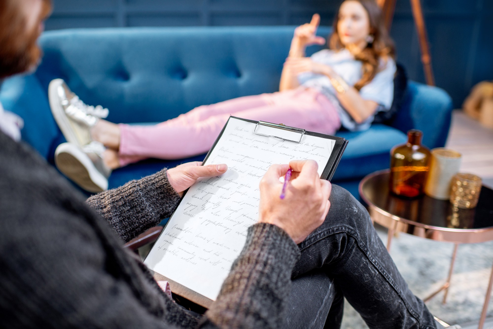 psychologist-writing-some-notes-while-listening-to-the-woman-client-during-psychological-session-indoors