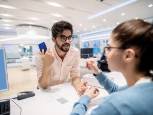 man-standing-on-cashier-and-complaining-for-new-smart-phone-while-worker-listening-to-him