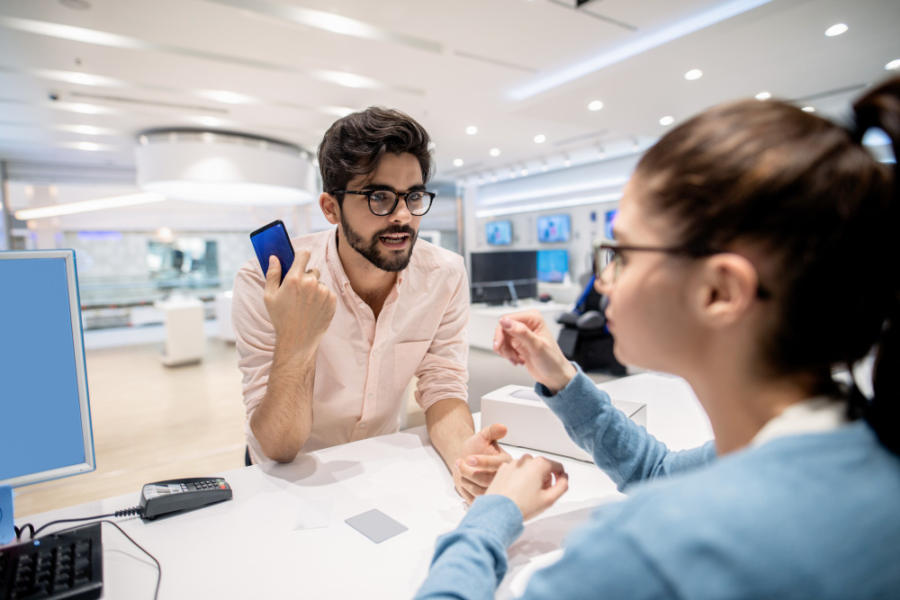 man-standing-on-cashier-and-complaining-for-new-smart-phone-while-worker-listening-to-him