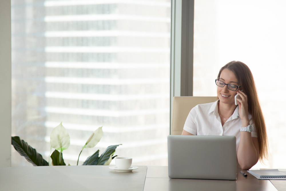 young-smiling-businesswoman-talking-on-phone-at-workplace-mobile-communication