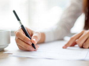 hand-of-businesswoman-writing-on-paper-in-office